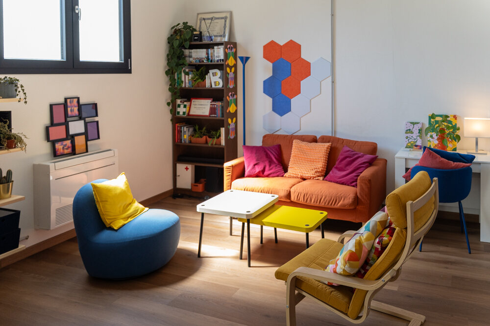 L'angolo lounge visto dalla finestra, con le poltrone gialla e blu e la libreria