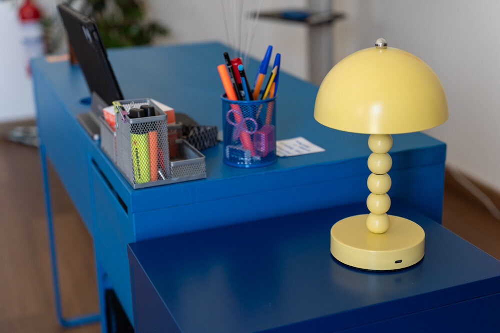La scrivania blu con la lampada gialla, i portapenne e i pennarelli pronti